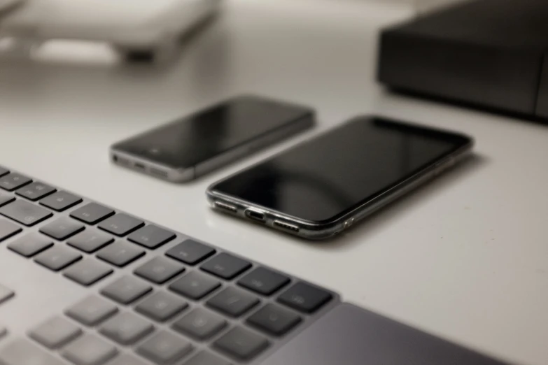 a couple of cell phones sitting on top of a keyboard