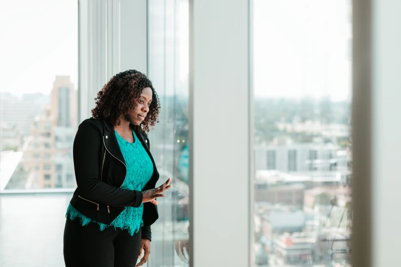 a woman standing next to a window looking at her cellphone