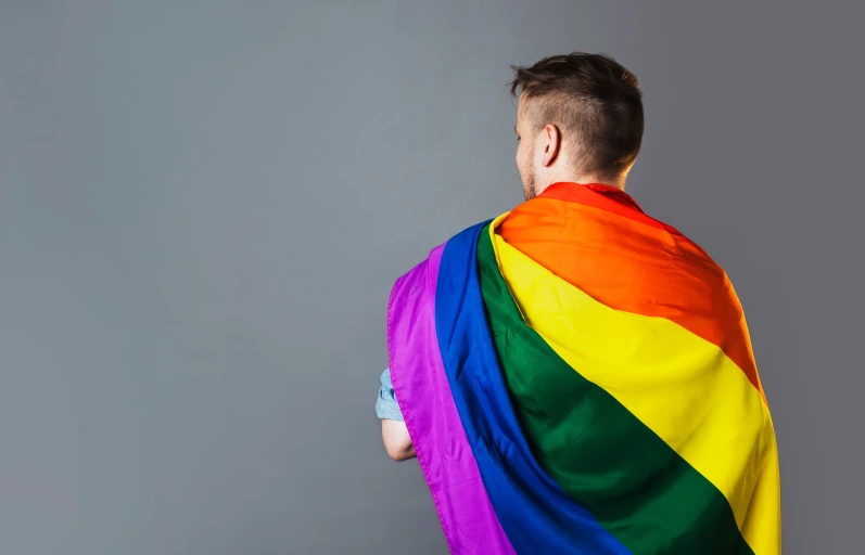 a man with a large rainbow colored shawl over his shoulders