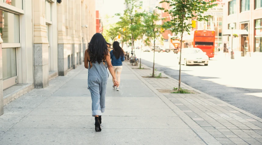 two young women walking down the sidewalk in the city