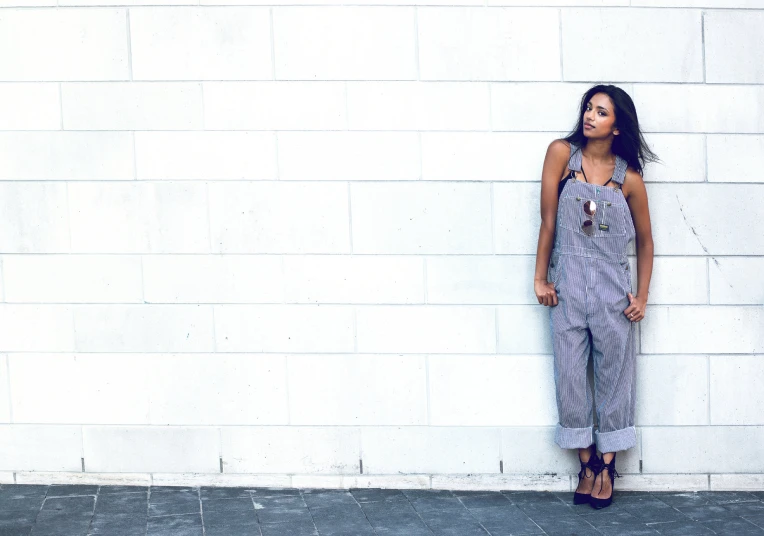 a person leaning on a white wall and wearing sandals