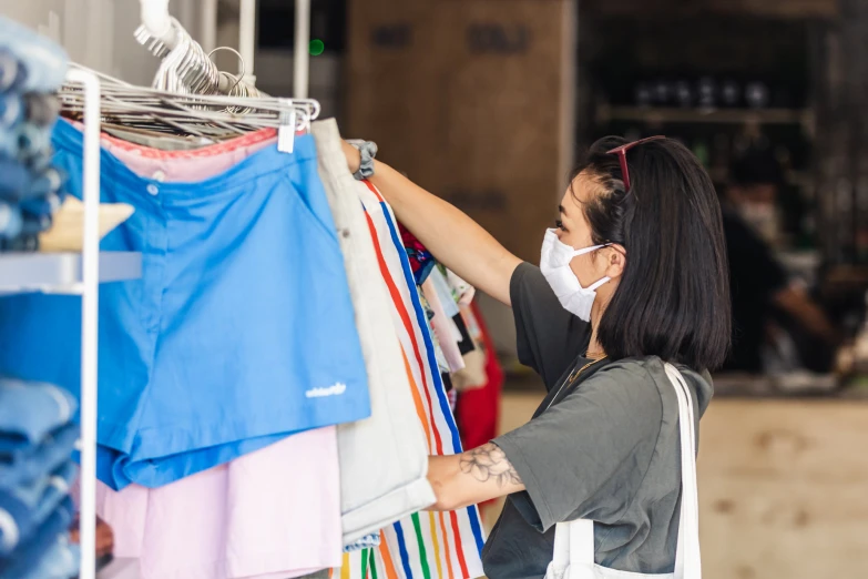 a woman is looking through clothing on rack