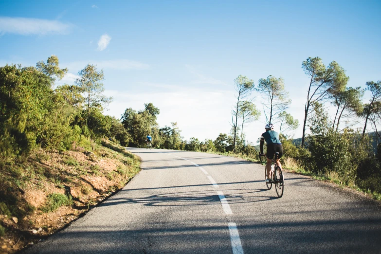 the man rides his bike down the middle of a deserted road