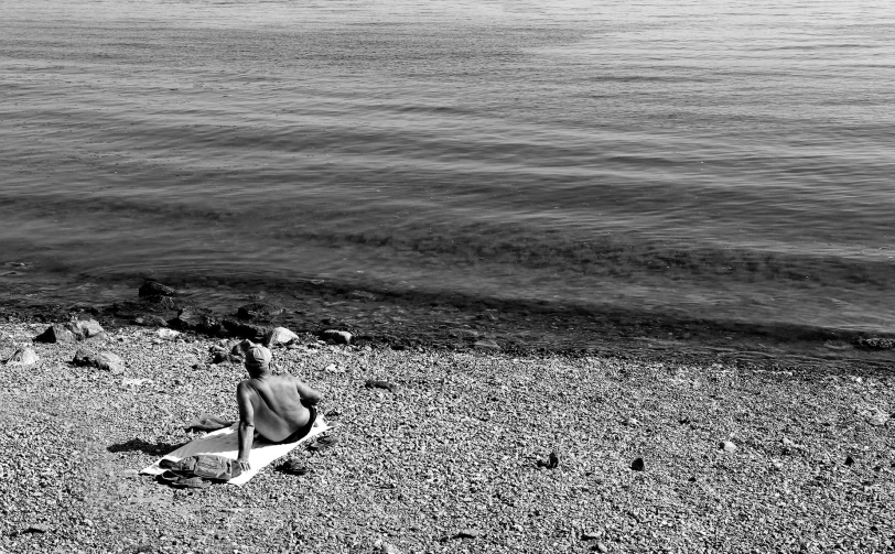 a person sitting on the shore of a body of water