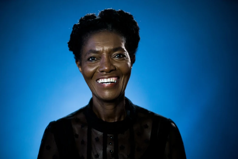 a black woman smiling with a blue background