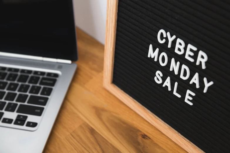 a black and white sign that says cyber monday sale next to a laptop