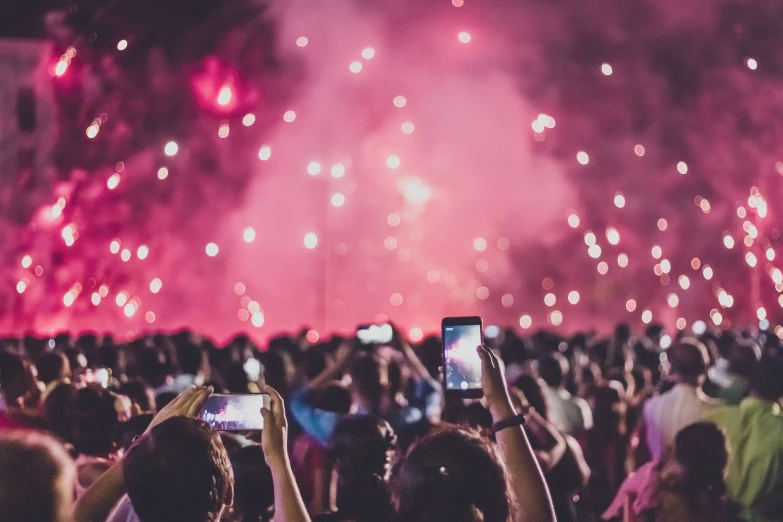 people holding up phones looking at fireworks