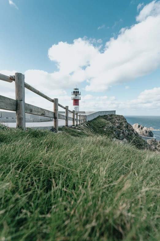 a wooden fence and a small light house on the water