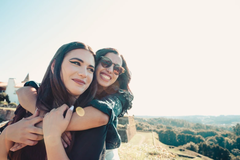 two women hug on a hill in front of a castle