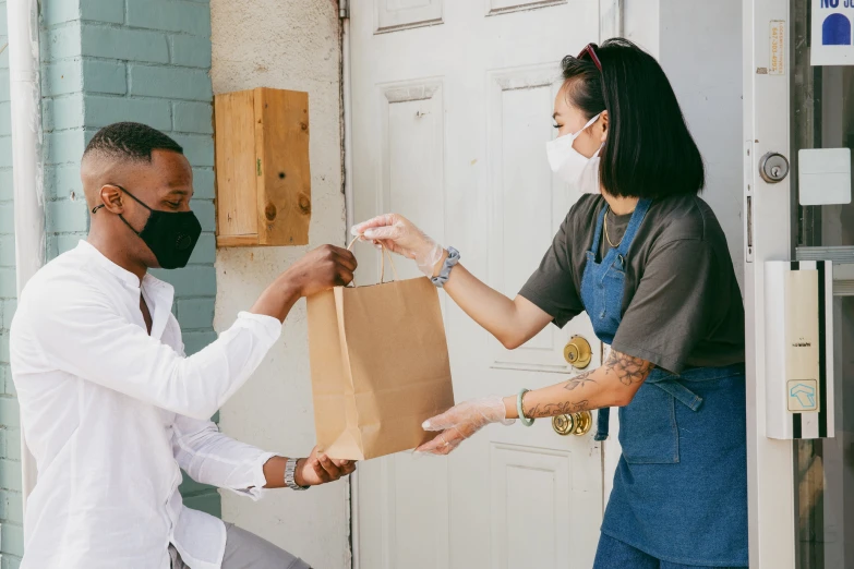 a man and woman in white shirts standing by the door of a house