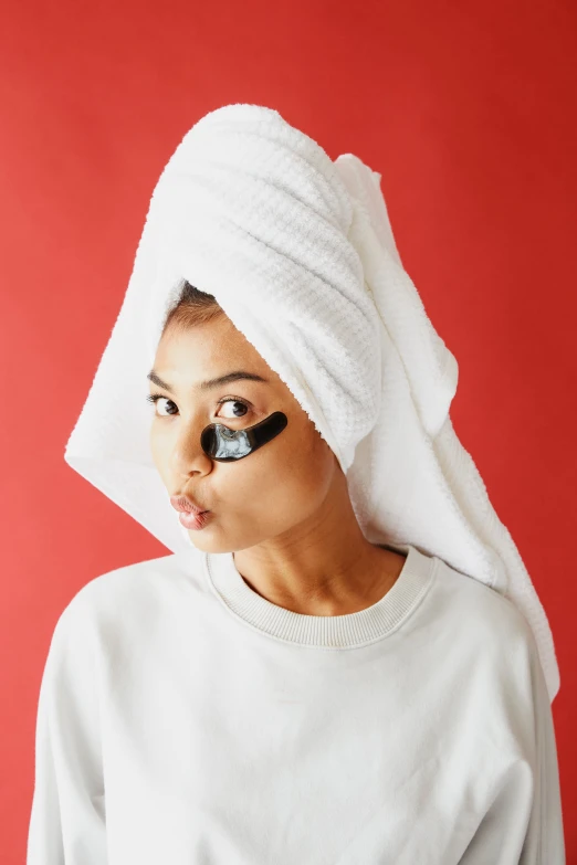a woman with black eyeliner under a white towel