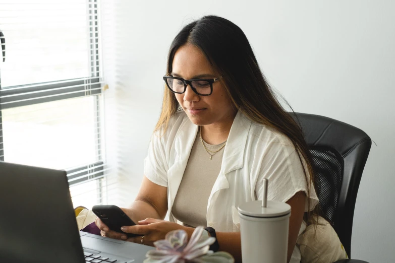 a woman in glasses is typing on her laptop computer