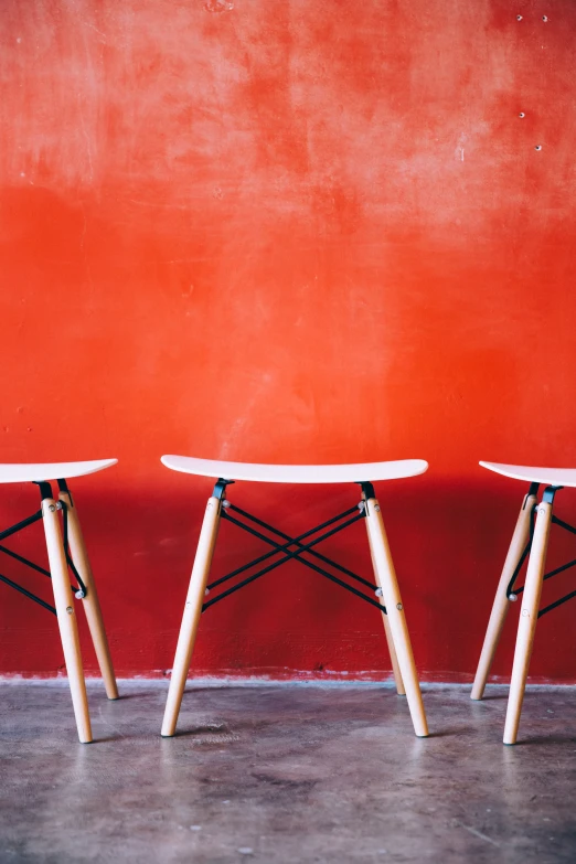 three chairs against a bright orange wall, one black and one white