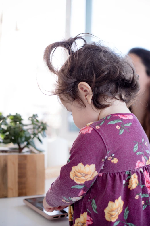 a child at a desk with flowered blouse and hair in a bun