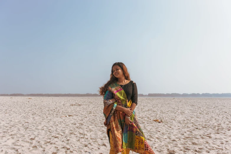 a woman is standing on the beach in a patterned dress