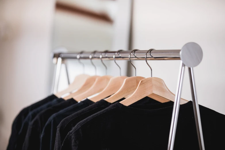 a number of t - shirts hanging on a rack with a mirror in the background