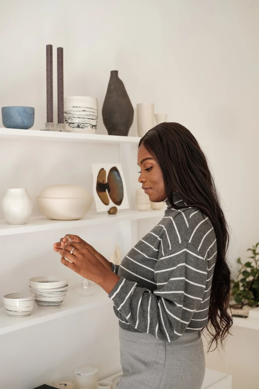 woman standing with glasses and looking at white dishes on a shelves