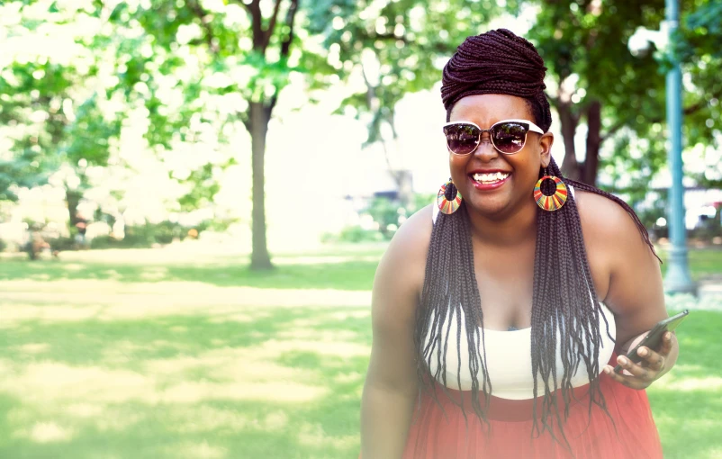 a woman wearing sunglasses and a colorful dress is smiling