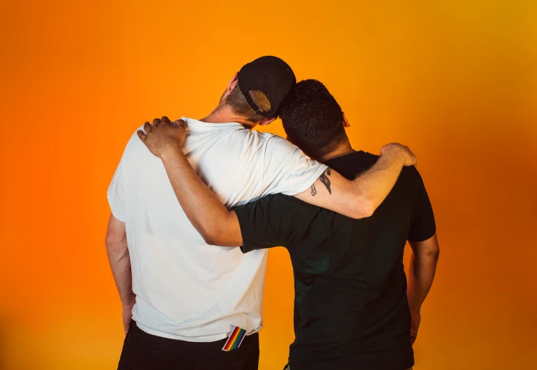 two men standing in front of an orange background emcing