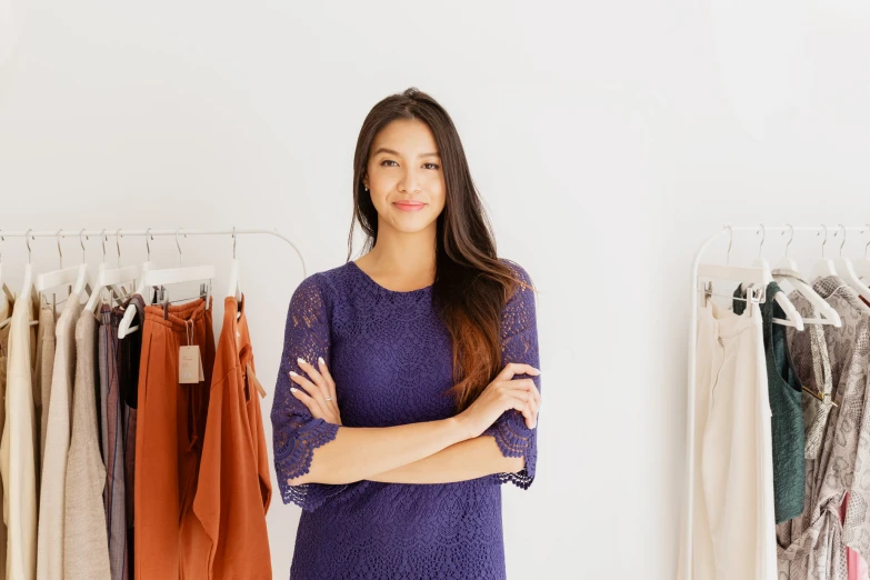 a woman in purple stands by a rack of dress