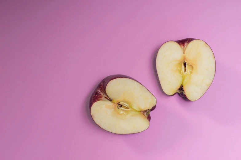 half a cut apple on a pink background