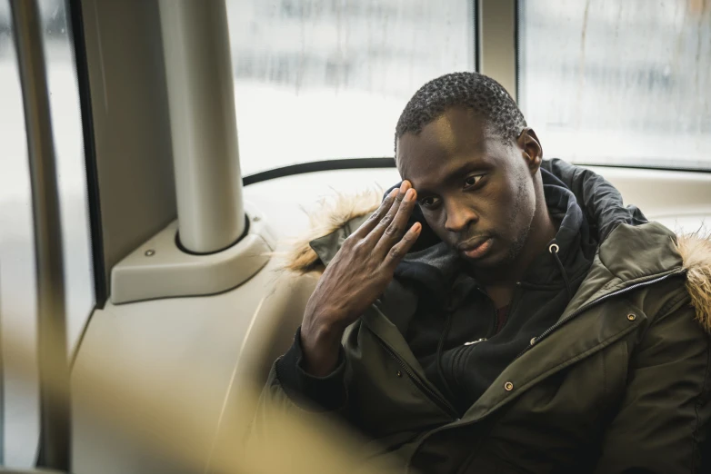 a man sitting inside of a bus while talking on the phone