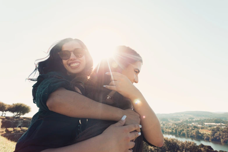 two women emcing each other with a lake and hills in the background