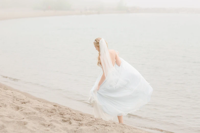 the bride is walking by the water on the beach