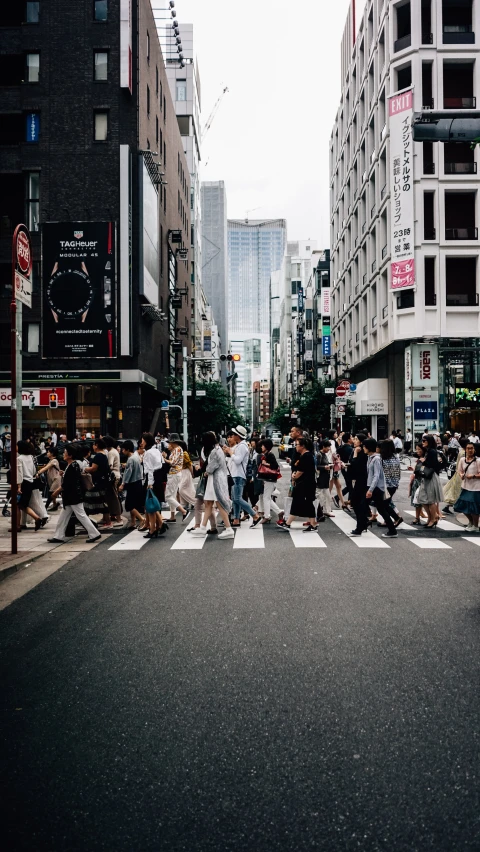 a city street filled with pedestrians and people crossing the street