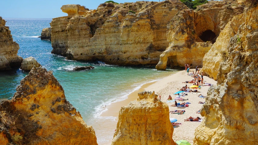 some people are on the beach near big rocks