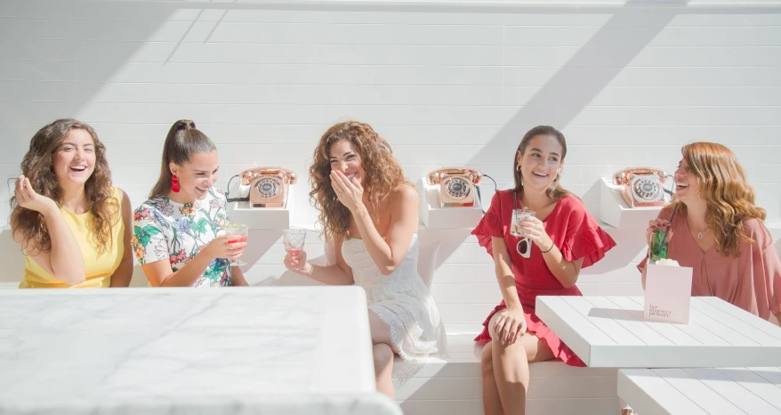 three women talking and sitting at white table with colorful vases