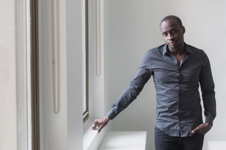 a man standing next to a window in a white room