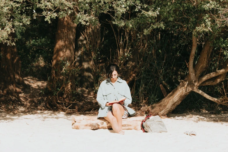 a woman sitting on the beach with her foot propped in the sand