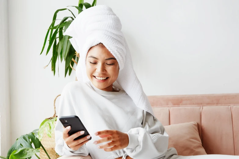 a woman in towel and sweater using her cell phone