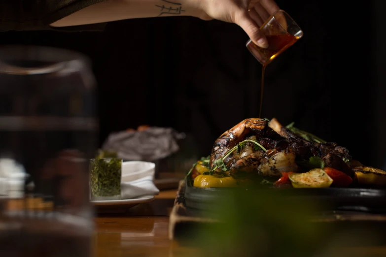 a person is pouring olive oil on food