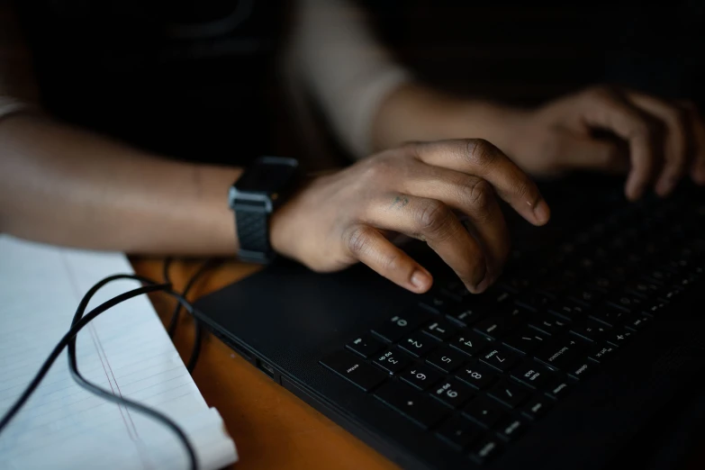 a person types on a laptop keyboard at night