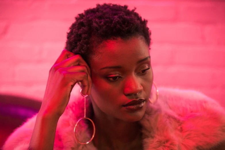 a woman in a red light is holding a large pair of hoop earrings