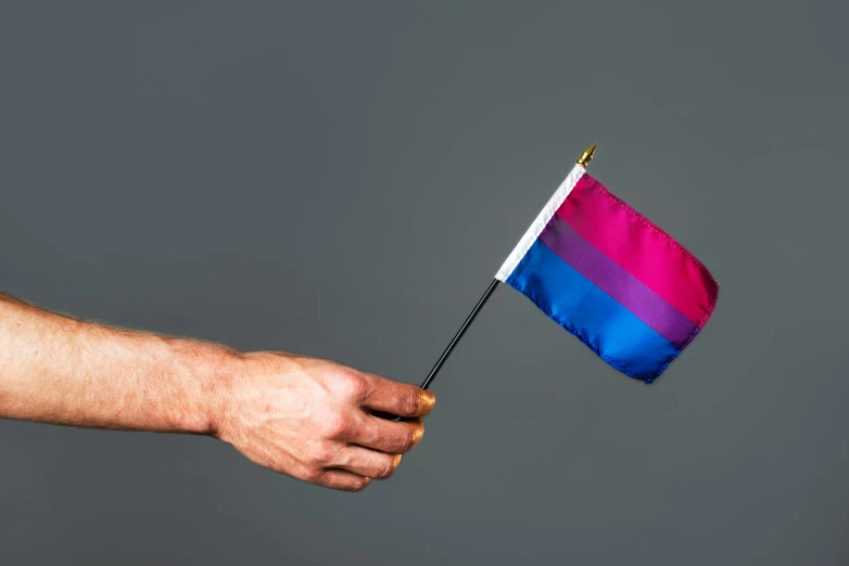 man holds a flag that flies on a metal pole