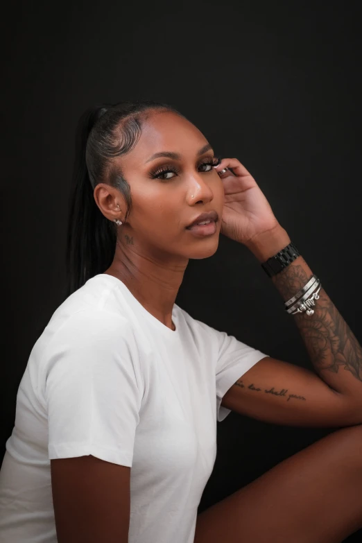 a black woman in white shirt sitting in front of a black background