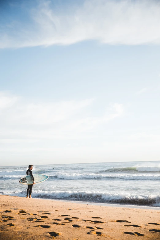 the man is carrying his surfboard along the beach