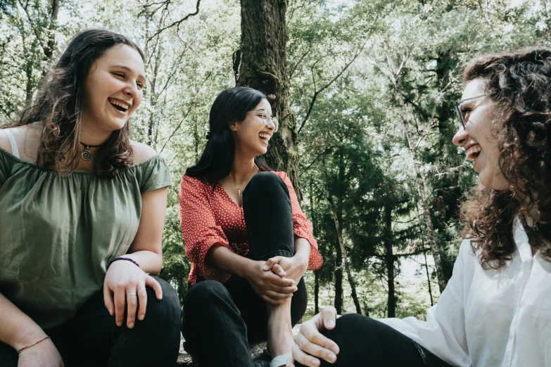 three women smile as they talk in the forest