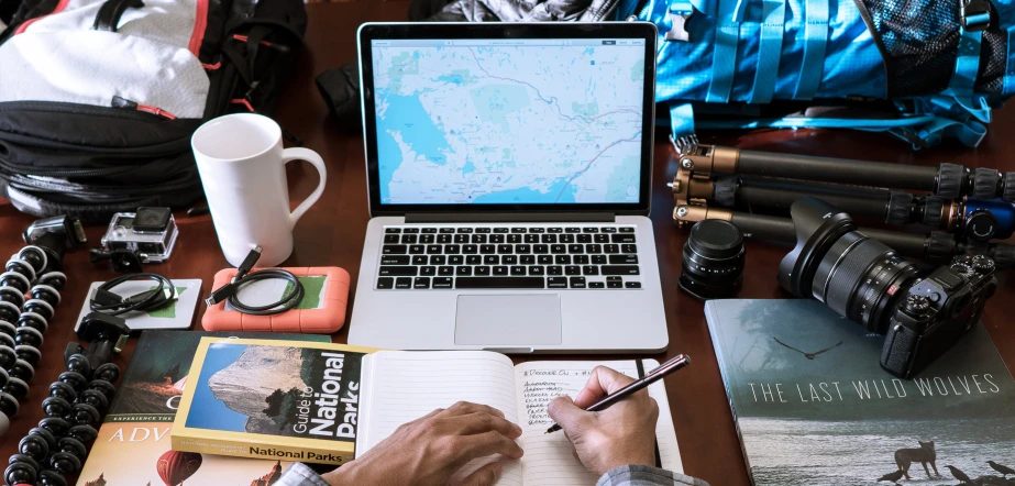 a man sits in front of his laptop while taking notes