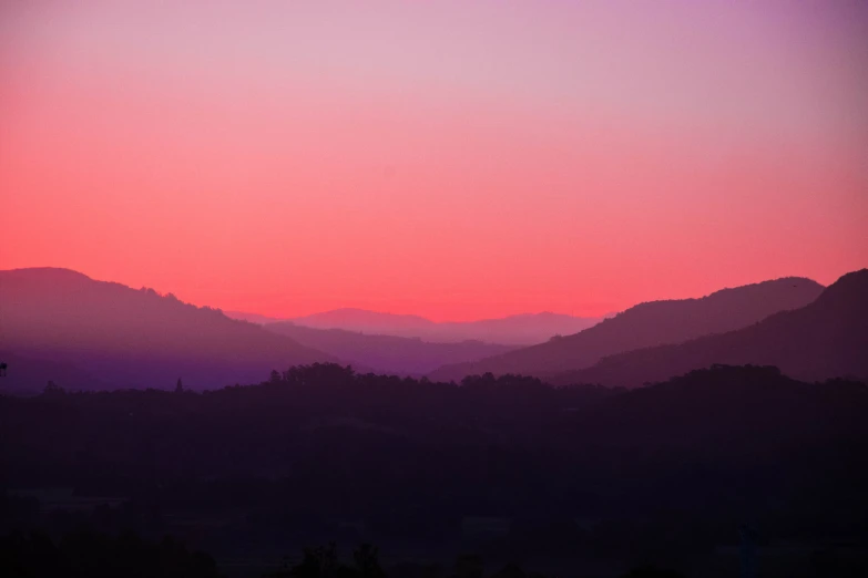 a sunset is seen through the mountains