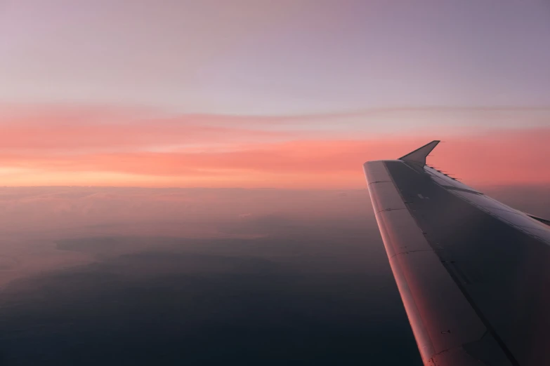 an airplane wing at dusk with clouds in the sky