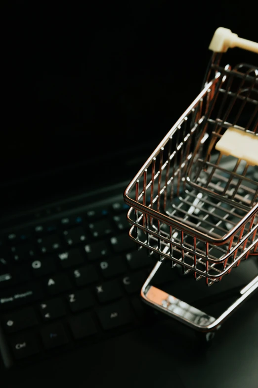 a miniature shopping cart sitting on top of a laptop computer