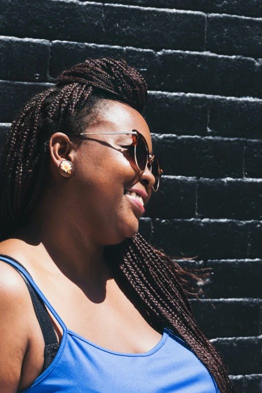 a woman with dreadlocks smiling and wearing sunglasses