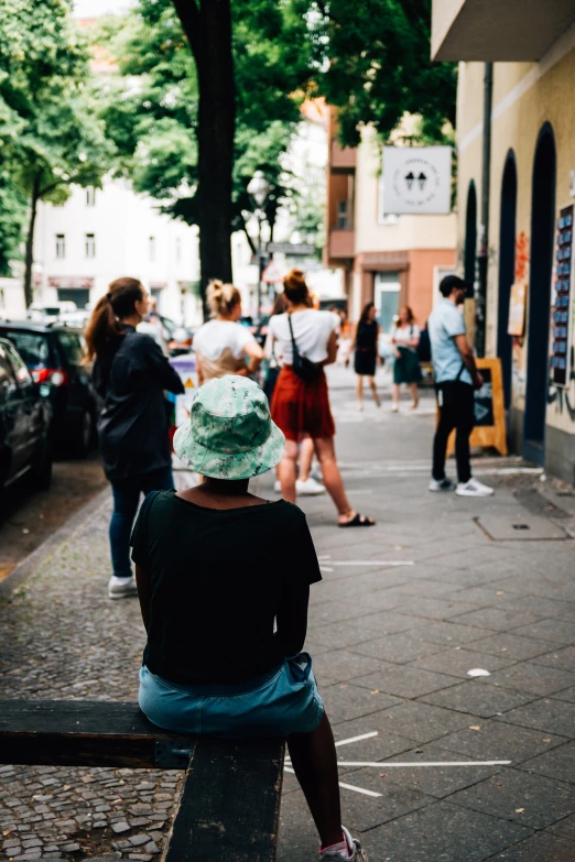 a person sitting on a bench next to cars