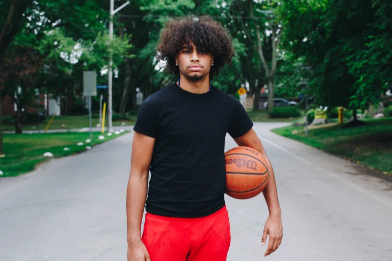 a man holding a basketball on a street