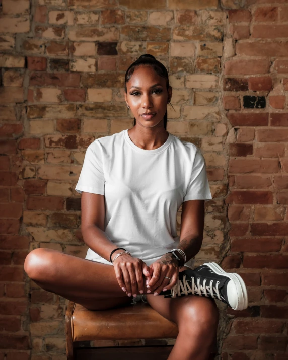 a black woman with white shirt and sneakers sitting on chair