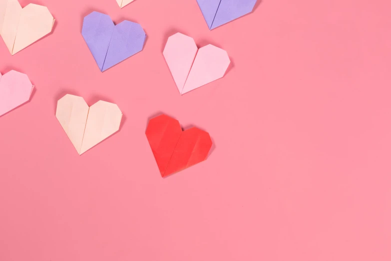 several hearts cut out of paper on pink background